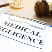 Clipboard with documents about medical negligence on a table. Clipboard with documents about medical negligence on a table.