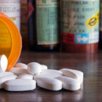 Prescription opioids with many bottles of pills in the background. Concepts of addiction, opioid crisis, overdose and doctor shopping