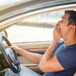 Asian young man driving a car and feel sleepy.