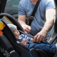 father putting kid in car seat father putting kid in car seat
