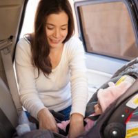 mother putting baby in car seat mother putting baby in car seat