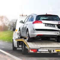 Loading broken car on a tow truck. Damage vehicle after crash accident on the highway road.