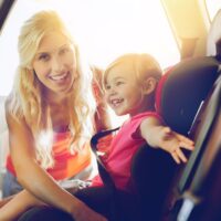 happy mother fastening child with car seat belt