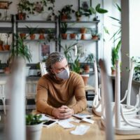 Frustrated owner sitting at table in closed cafe, small business lockdown due to coronavirus. Frustrated owner sitting at table in closed cafe, small business lockdown due to coronavirus.