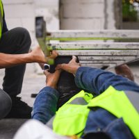 Accidents of builder in the workplace at construction site area, Builder accident falls ladder and lying on floor while foreman is helping. Working unsafe concept.