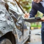 Insurance agent examining car after accident claim being assessed and processed