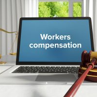 Workers compensation. Law. A lawyer laptop on a desk in the office. Text on the screen. Libra, Juctice, Web Workers compensation. Law. A lawyer laptop on a desk in the office. Text on the screen. Libra, Juctice, Web