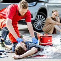 paramedic-in-red-uniform-performs-cpr-on-an-injured-person-lying-on-a-crosswalk