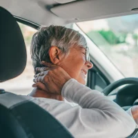rear-view-of-old-woman-having-neck-pain-while-driving-a-car rear-view-of-old-woman-having-neck-pain-while-driving-a-car