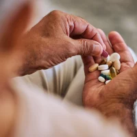 senior man taking daily capsules for chronic illness