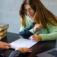 Injured woman signing compensation contract during meeting with lawyer