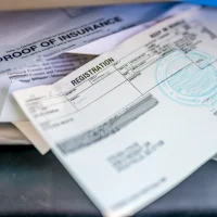 Proof of insurance and vehicle registration documents in the glove compartment of a car.